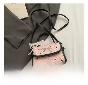 Detail of pink bow-print crossbody bag featuring pearl lace charm and silver hardware