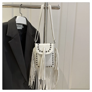 Close-up of white bohemian crossbody bag with metallic studs and long tassel details