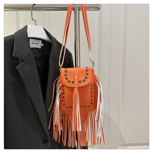 Detail of orange tassel crossbody bag with metallic rivets on a lychee grain leather finish