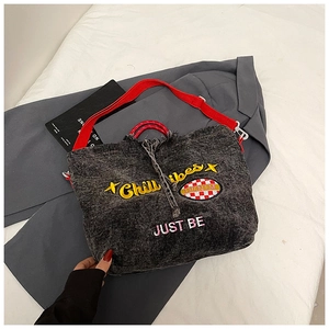 Detail of grey denim tote bag with yellow CHILL vibes embroidery and red strap handles