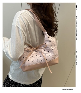 Detalle de bolso de hombro acolchado rosa claro con bordado de lazos negros delicados