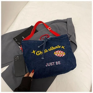 Detail of blue denim tote bag with 'Chill vibes' embroidery and red straps