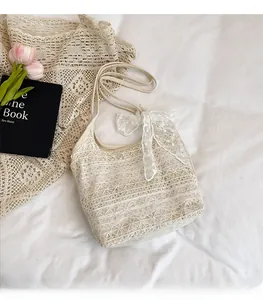 Detailed close-up of cream lace tote bag with floral crochet patterns and bow detail