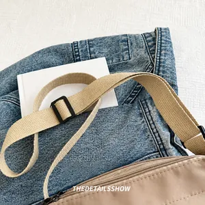 Détail de la large bandoulière en toile kaki sur le sac à bandoulière en nylon marron