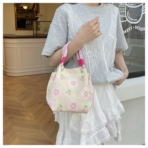 Detail of knitted mini bucket bag with cherry pattern and pink rope handle