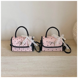 Detail view of pink mini crossbody bags with black bow and heart patterns and lace accents