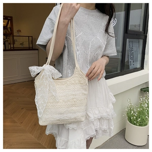 Détail du sac cabas en dentelle blanche avec motifs ajourés et un grand nœud décoratif