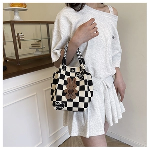 Detail of checkered knit handbag featuring a cute brown rabbit patch embroidery