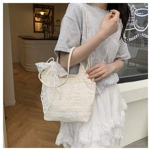 Detail of a creamy lace tote bag with a delicate bow on a shoulder in a cafe setting