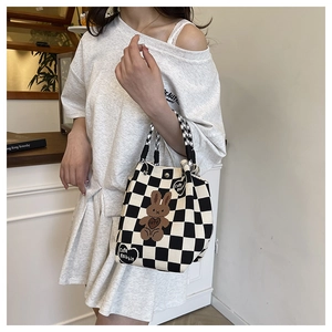 Close-up of black and white checkered knit bag with brown plush rabbit embroidery detail