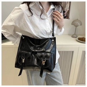 Detailed view of large black patent leather tote bag with decorative metal buckle pockets