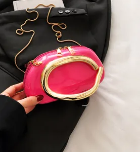 Detail of pink patent leather handbag with gold U-shaped handle and metal dual zippers
