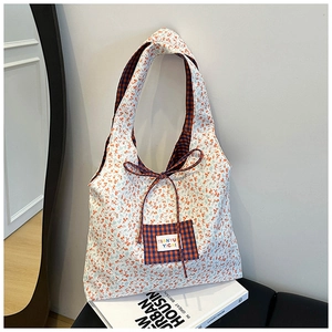 Close-up of floral canvas tote bag showing checked pocket and tie closure details