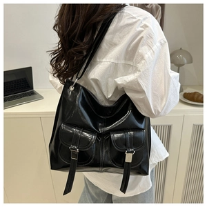 Detail of black glossy leather tote bag showing double front pockets and large capacity