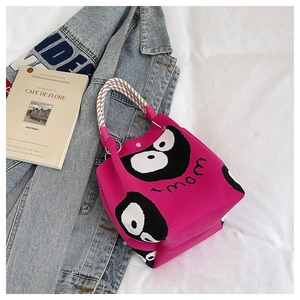 Close-up of pink knitted bucket bag featuring monster eyes and colorful rope handle
