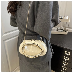 Detail of a creamy white half-moon bag featuring a large polished gold metal ring buckle