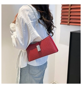 Detalle de bolso rojo de cuero trenzado con cierre giratorio plateado y cadena
