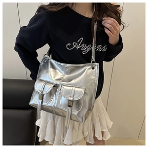 Detail view of large silver metallic tote bag with two front pockets on a model