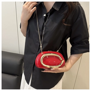 Macro shot of red patent leather crossbody bag with iconic gold C-shaped metal handle