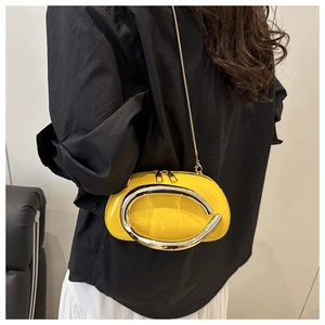 Detail of yellow patent leather handbag featuring a large silver C-shaped metal handle
