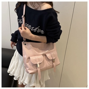 Detail of pink glossy patent leather motorcycle tote bag with buckle pockets on model