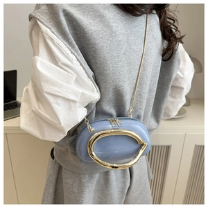 Close-up of light blue mini crossbody bag with glossy finish and gold metal ring handle