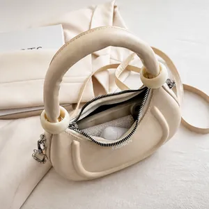 Détails de l'intérieur du sac lune blanc crème avec rouge à lèvres et écouteurs sans fil