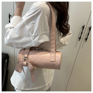 Primer plano detallado de un bolso cilíndrico rosa con un gran colgante decorativo de lazo