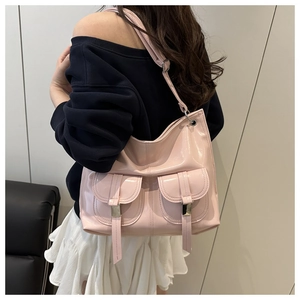 Detail shot of pink patent leather tote bag with dual front pockets and glossy metallic buckles