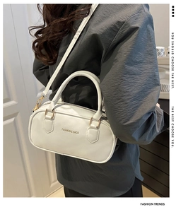 Detail of white leather bowling bag showing fashion text print and gold hardware