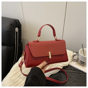 Détail du sac à main rouge avec boucle dorée présenté dans un cadre de café élégant