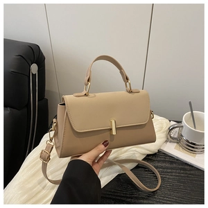 Détail d'un sac à main en cuir beige clair avec fermoir doré cylindrique et poignée