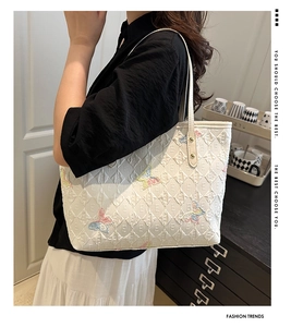 Détail du sac cabas matelassé blanc avec broderies papillons colorées et rivets en métal