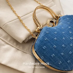 Détail du crochet doré et du sac cœur en jean bleu avec poignée ornée de strass