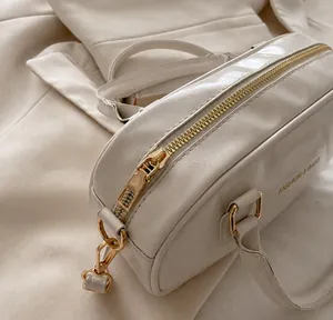 Detail of cream white leather bowling bag with gold zipper and smooth texture