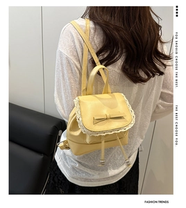 Détail d'un mini sac à dos jaune avec bordure en dentelle blanche et nœud élégant