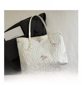 Détail d'un cabas blanc matelassé avec broderies papillons colorées et grande contenance