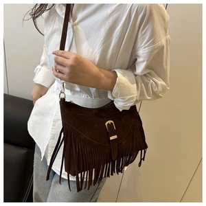 Detail of dark brown suede crossbody bag featuring long fringes and metal buckle clasp