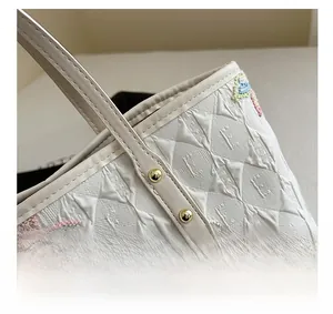 Détail macro du cabas beige avec broderies étoiles et rivets métalliques dorés