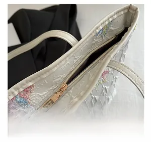 Détail de la fermeture éclair et des broderies papillons sur le sac fourre-tout blanc
