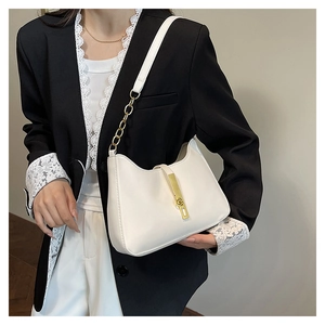 Detail of a white faux leather hobo bag with gold metal clasp and chain strap on a model
