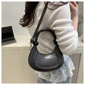 Détail du sac croissant noir avec lettrage fashion et boucle métallique de la bandoulière