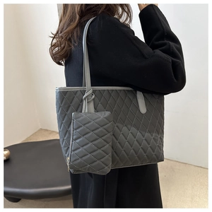 Vue détaillée du sac cabas matelassé gris avec petite pochette porté à l'épaule sur manteau