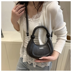 Détail du sac à main croissant noir avec lettrage blanc et bandoulière amovible