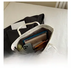 Vue intérieure d'un grand sac cabas blanc gaufré montrant les essentiels et un parapluie
