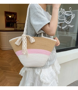 Detail of tricolor woven tote bag with large lace bow and thick rope handles for summer