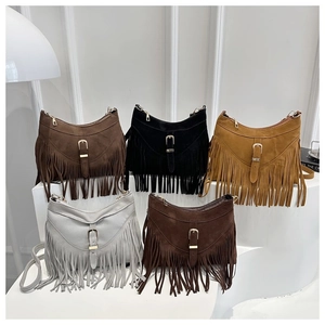 Detalle de bolsos bohemios con flecos en cinco colores con textura de ante y hebilla de cuero