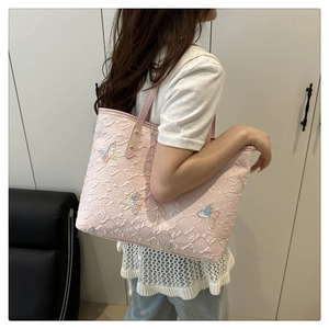 Détail du cabas rose avec broderie papillon en paillettes et motif monogramme de marque