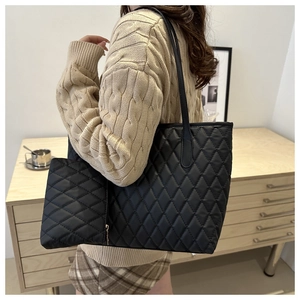 Détail du grand sac cabas noir matelassé avec pochette zippée porté par un mannequin