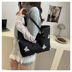 Détail du sac cabas noir avec lettrage gaufré et broderies de papillons multicolores